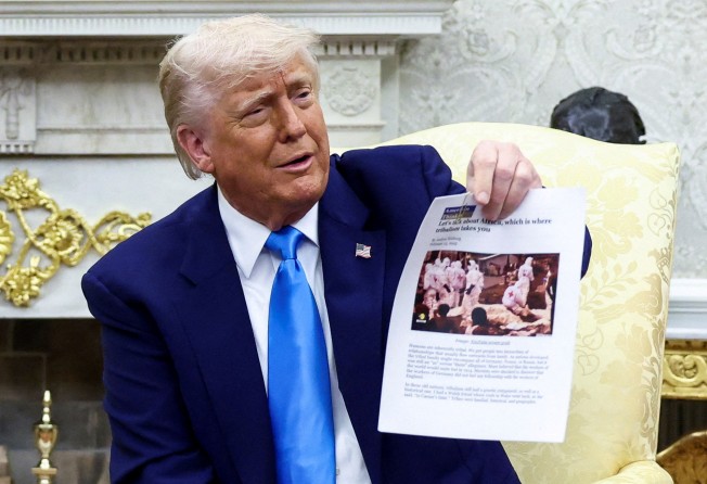 US President Donald Trump shows a copy of an article that featured an image showing Red Cross workers in protective gear handling body bags. Photo: Reuters