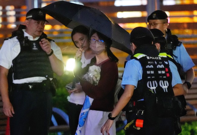 A youngster in school uniform and holding a bouquet is stopped by police. Photo: Elson Li