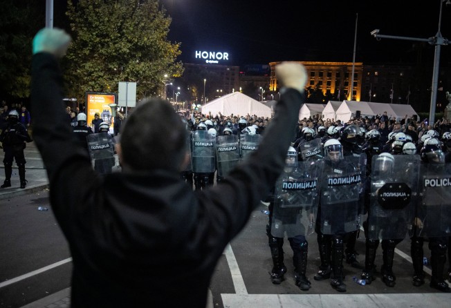 An anti-government demonstrator gestures in front of riot police near the parliament in Belgrade, Serbia, on Sunday. Photo: Reuters