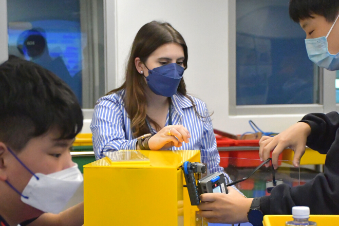 Ms Tizzard working with Grade 8 students in the STEMinn lab on their final VEX IQ automated delivery robot challenge project.