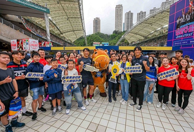 Club Chairman Michael Lee (front row, 6th right) and CARE@hkjc Volunteer Team members greet young beneficiaries of the Jockey Club Sevens Community Experience and Hong Kong China Men’s Sevens team members Salom Yiu (front row, 6th left) and Wesley Ng (front row, 4th right) at the Jockey Club booth.