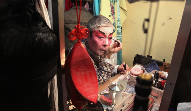Cantonese opera performer, Yuen Siu-Fai, applying makeup back stage during a performance of "The Lion's Roar"