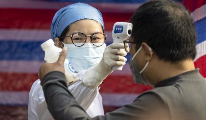 A medical worker takes the temperature of a man at a checkpoint in the southern city of Guangzhou.