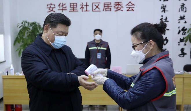 Chinese President Xi Jinping takes a temperature during a public appearance at a community health center in Beijing. 