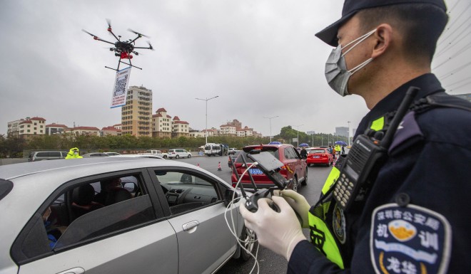 A police officer operates a drone carrying a QR code to check registered vehicles entering Shenzhen. High tech tools have been relied upon to fight the coronavirus epidemic.  
