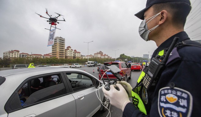 A police officer operates a drone carrying a QR code to check registered vehicles entering Shenzhen. High tech tools have been relied upon to fight the coronavirus epidemic.