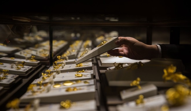 An employee handles a gold jewellery set inside a display case at a Chow Tai Fook shop in Hong Kong. The gold and jewellery retailer has more than 4,000 outlets worldwide. Photo: Bloomberg