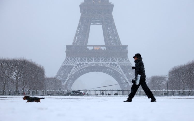 A woman walks her dog in a snow-covered area in front the Eiffel Tower in Paris, France. Photo: Reuters