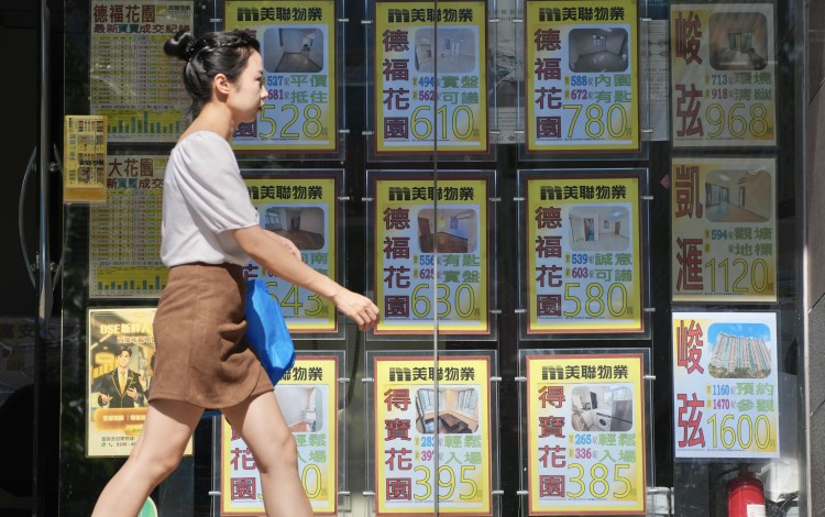 A woman walks past a real estate agency office displaying advertisements for residential listings in Telford Plaza, Kowloon Bay, on August 16, 2026. Photo: Karma Lo