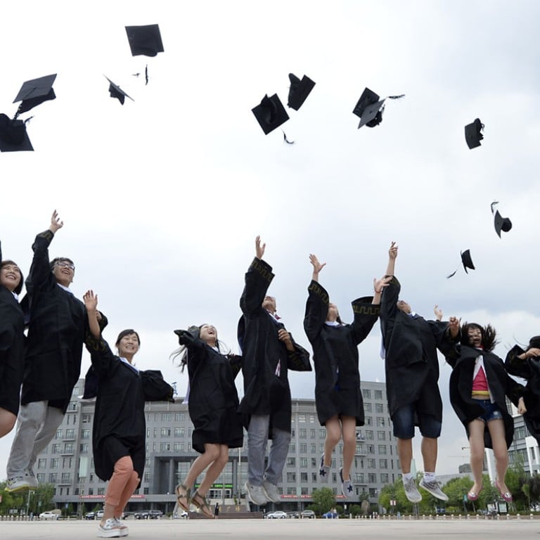 A group of diverse students in graduation gowns are joyfully celebrating by tossing their caps into the air outdoors against a backdrop of a modern building and cloudy sky.
