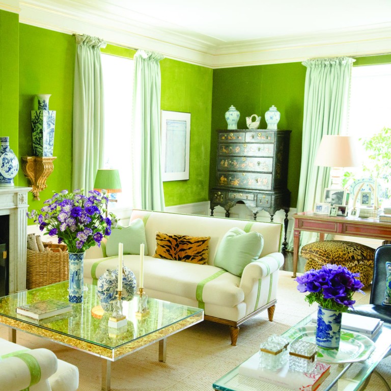 The living room features cool olive walls and pistachio curtains offset by striped cream furniture and a stunning coffee tablein gold.