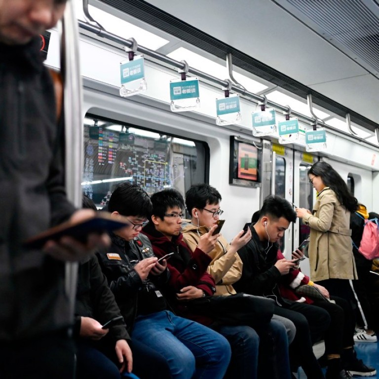 Students play online games inside a subway train in Beijing