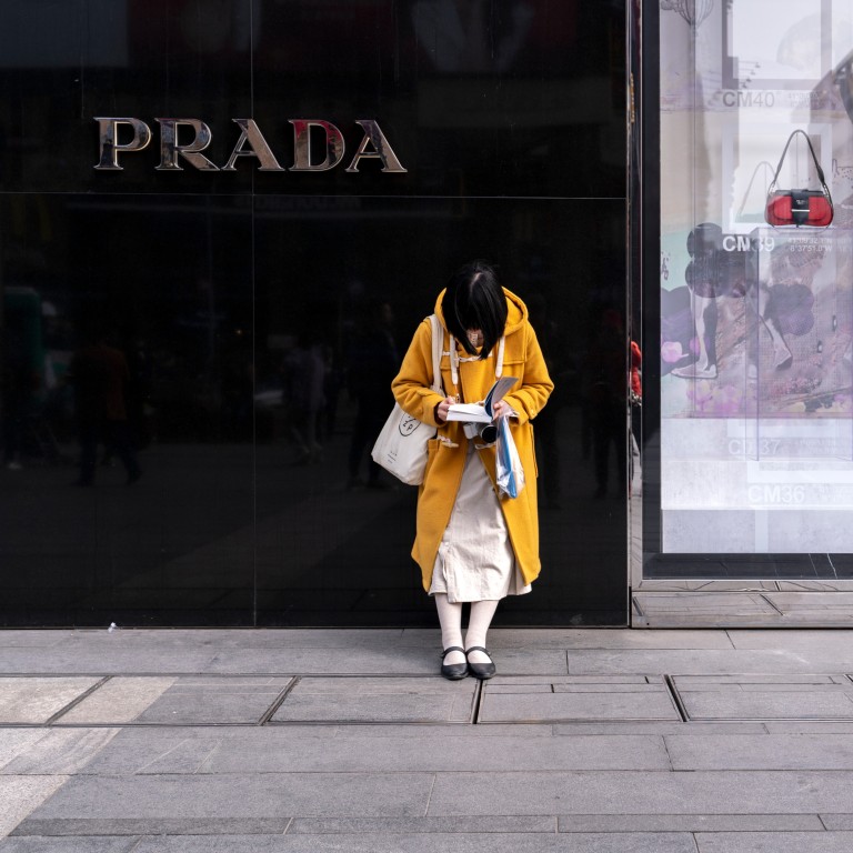 A woman reads a book outside a Prada store in Chengdu in March 2019. China is on course to be the world’s biggest luxury market by 2025. Photo: Shutterstock