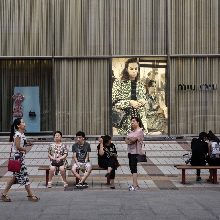 Shoppers sit in front of luxury store Miu Miu in an upscale shopping district in Beijing, China. Photo: Getty Images