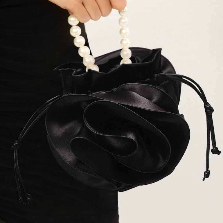 Discover the understated elegance of rose-shaped bags this spring, with unique creations from Burberry, Magda Butrym, and Thom Browne. These floral-inspired designs offer a refreshing twist to your evening essentials. Pictured: Pearl Magda bag in black satin, by Magda Butrym. Photos: Handout