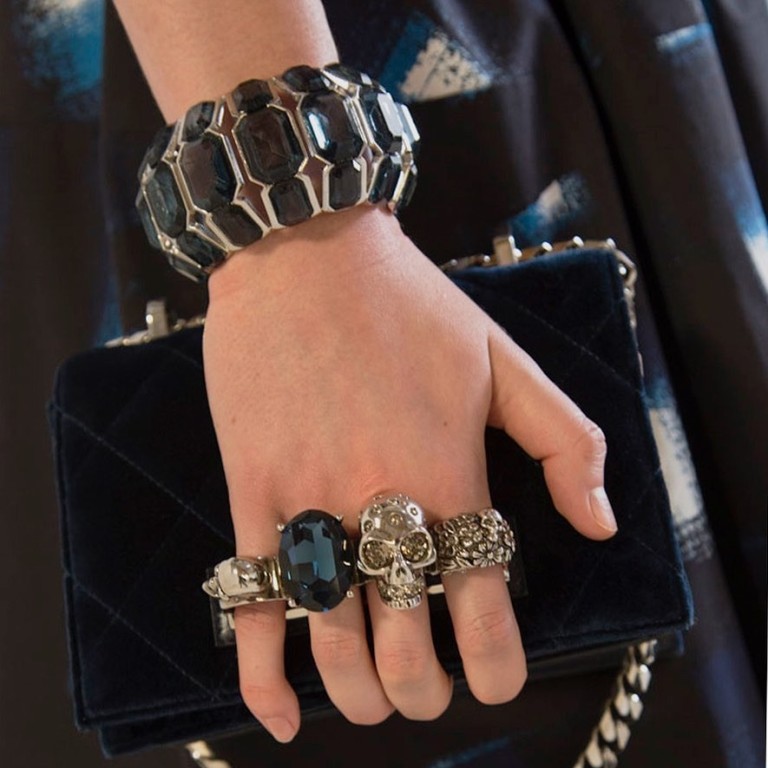 Logos in luxury goods seem to become smaller as the price rises, as seen in this small jewelled Alexander McQueen clutch in night-blue velvet matelassé with silver hardware.
