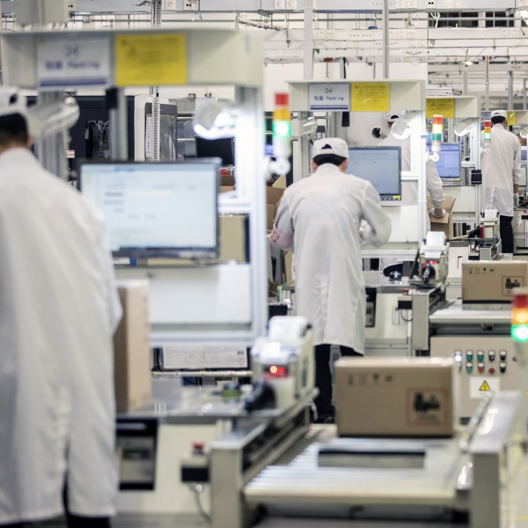 A robot passes employees working on a mobile phone assembly line at a Huawei Technologies Co. production base in Dongguan. Photo: Bloomberg