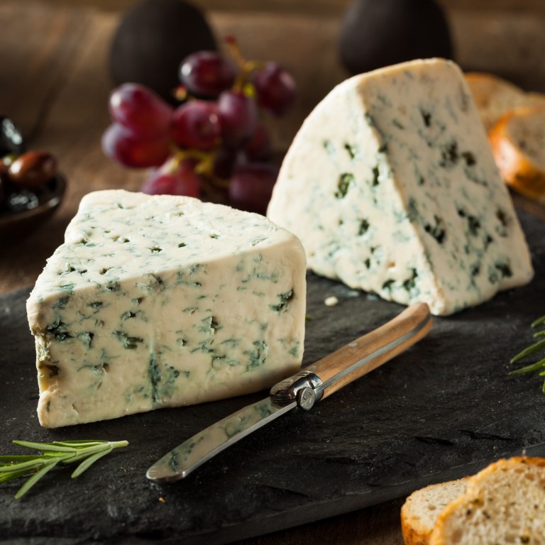 Blue cheese is accompanied by olives and grapes.