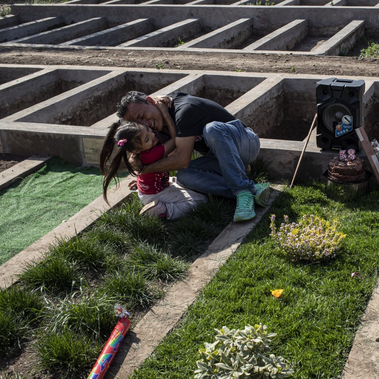 A girl embraces her father as they visit his wife’s grave, who died of the coronavirus in Santiago, Chile. Photo: AP