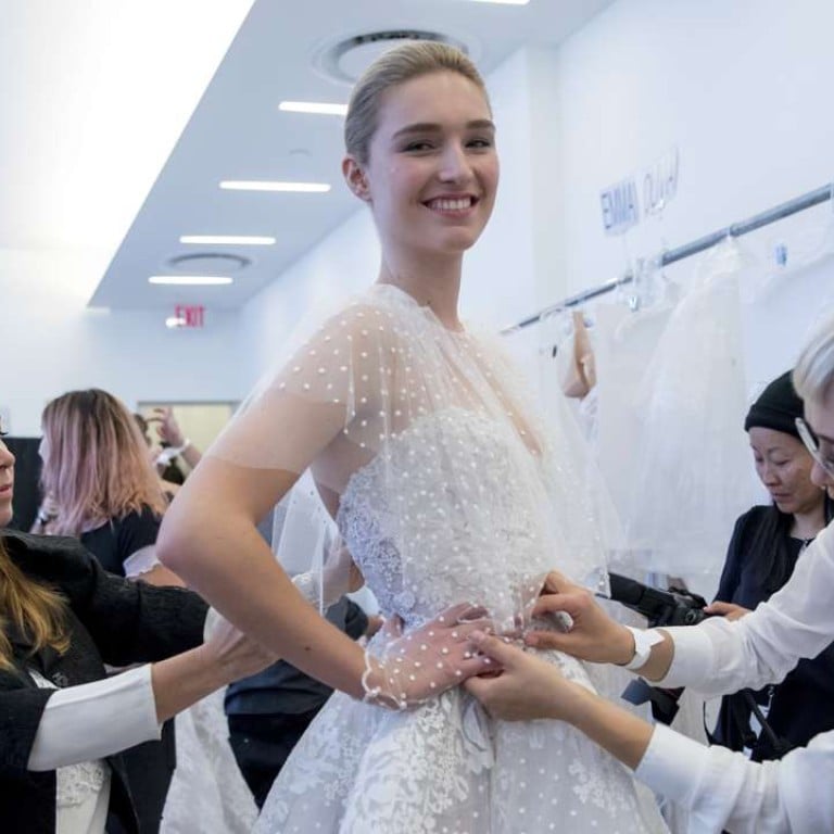 Designer Monique Lhuillier, left, adjust a dress on a model ahead of her collection presentation during Bridal Fashion Week in New York. Photo: AP