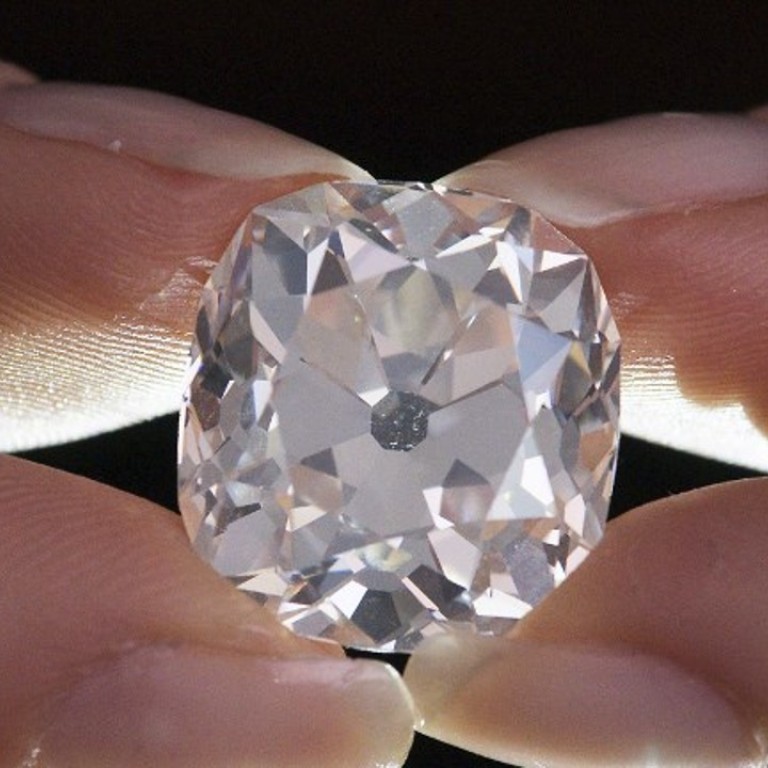 A member of Sotheby's staff poses holding a 26.27 carat, cushion-shaped, white diamond, for sale at Sotheby's auction house. Photo: AFP