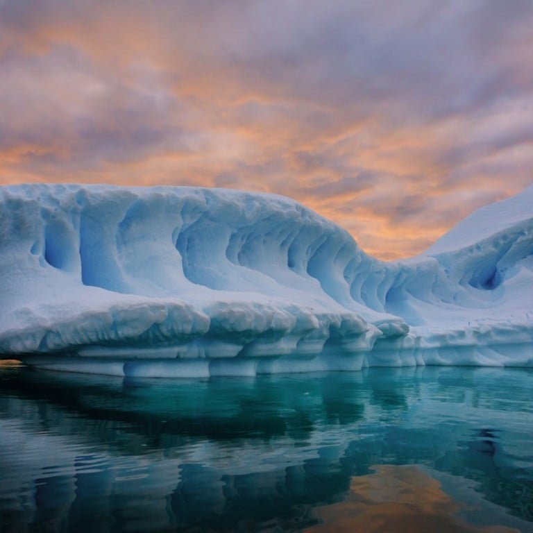 Iceberg - A warm sunset glowing over a floating iceberg in the Lemaire Channel, Antarctica.