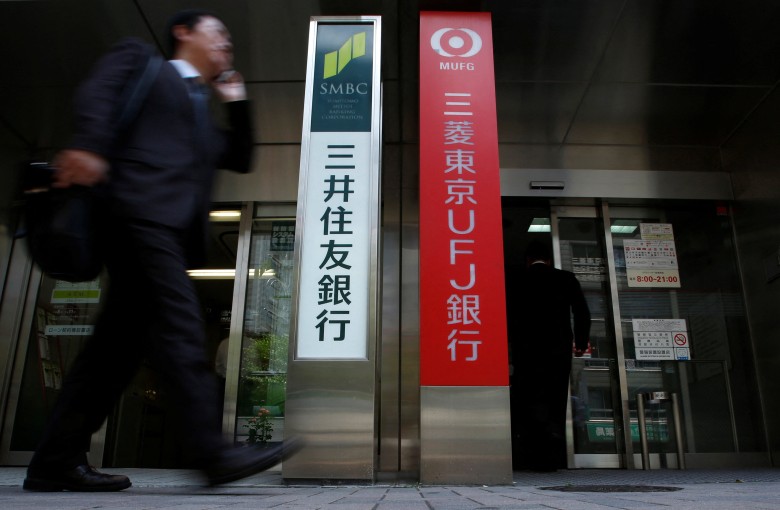 A man walks past ATM booths for Japan’s mega banks, Sumitomo Mitsui Banking Corporation, left, and Bank of Tokyo-Mitsubishi UFJ, in Tokyo, on February 6. Photo: Reuters