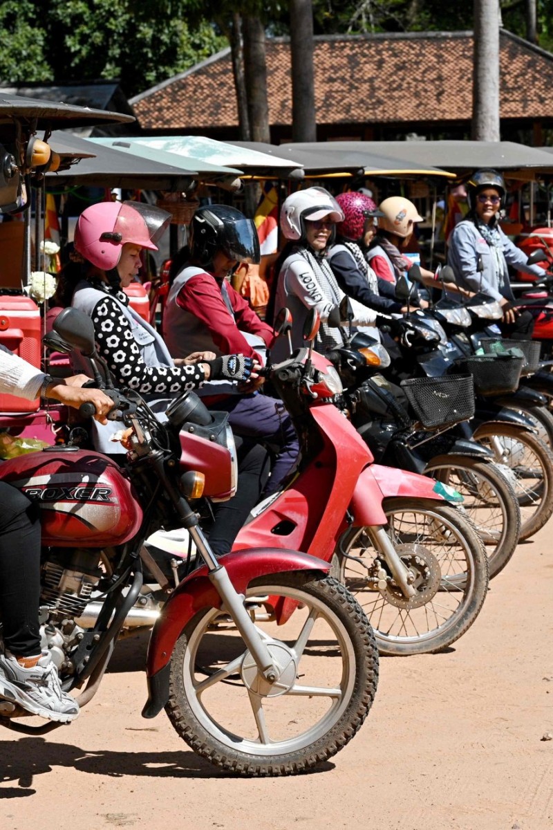 A Cambodian girl is sqeezed between a driver and a passenger of an  overloaded motorbike taxi in the capital Phnom Penh, Tuesday, April 4,  2006. Overloaded motorcycles and cars are a common