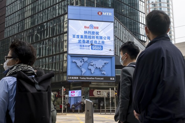 Pedestrians in front of a display for the listing of Baidu on the Hong Kong Stock Exchange on March 23, 2021. Photo: Bloomberg