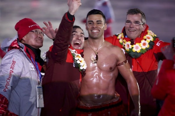 Tonga flag bearer Pita Taufatofua poses with a volunteer and teammates during the opening ceremony of the 2018 Winter Olympics in South Korea. Photo: AP
