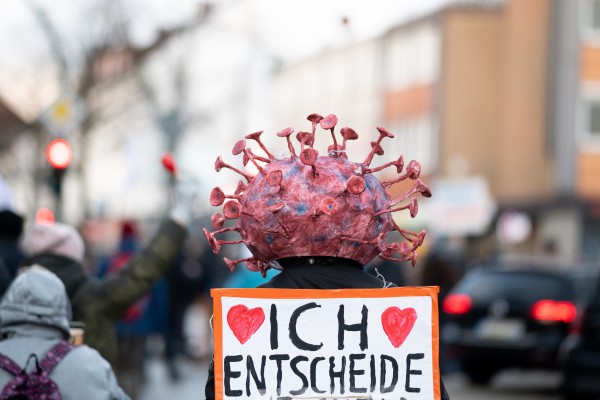 A protester wears headgear with a stylised virus on it during a demonstration against coronavirus policies in Hamburg, Germany on January 22. Photo: DPA