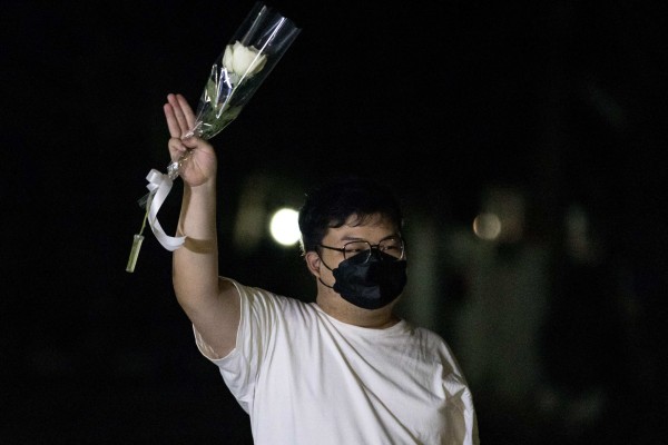 Pro-democracy activist Parit ‘Penguin’ Chiwarak waves a white rose and gives a three-fingered salute. Photo: AFP