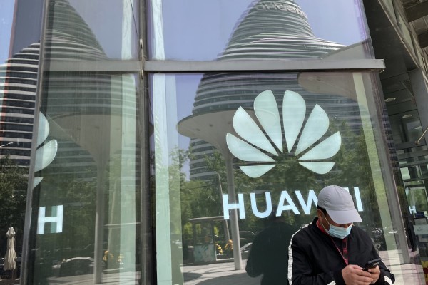 A man uses his smartphone in front of a Huawei logo in Beijing, April 27,  2022. Photo: SCMP/Simon Song