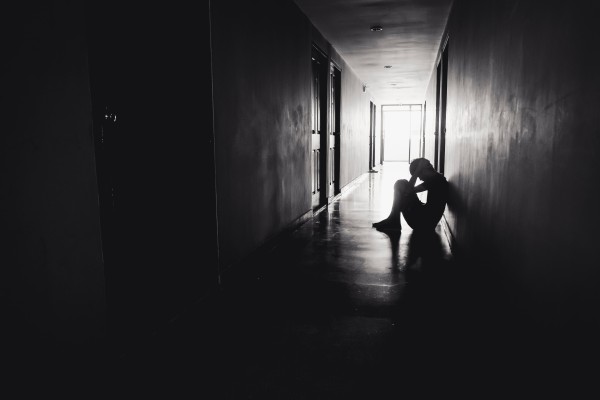 Silhouette of sad depressed man sitting head in hands on the floor. Photo: Shutterstock