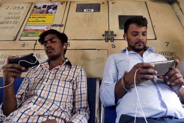 Commuters watch videos on their mobile phones as they travel in a suburban train in Mumbai, India. File photo: Reuters