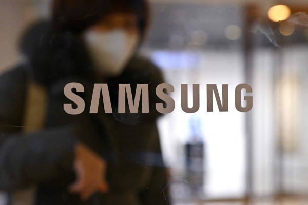 A woman walks past the Samsung logo displayed on a glass door at the company’s Seocho building in Seoul, January 31, 2023. Photo: AFP