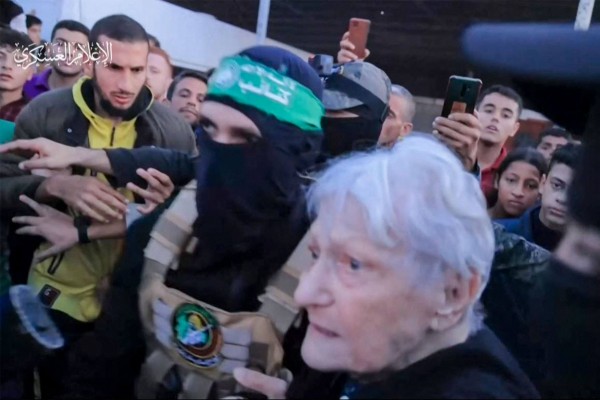 A member of Hamas’ Al-Qassam Brigades leading a hostage (right) over to officials from the International Committee of the Red Cross in Gaza on Friday. Photo: Hamas Media Office via AFP