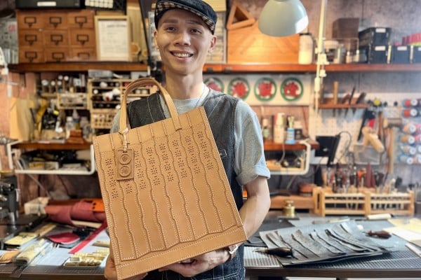 Hong Kong leather accessories maker Nardos Vintage’s founder, Heison Kwok, with the first bag he designed, its pattern inspired by the folding cast iron gates of old-established shops in the city. Photo: Kylie Knott
