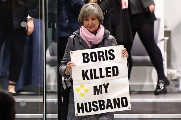 A woman carries a sign reading “Boris killed my husband” as she leaves the UK Covid-19 Inquiry in London on Thursday. Photo: AFP
