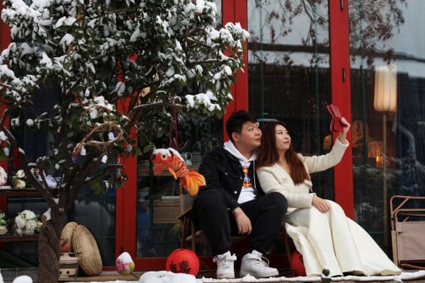 A couple poses with their marriage certificate during a photo shoot on a snowy day in Beijing, China on December 11. Photo: Reuters
