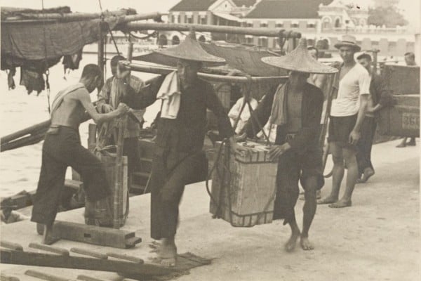 Stevedores at the wharf, circa 1900s. Stevedores have long played a crucial role as an essential workforce in the freight transport industry. From the 19th century, they toiled daily in harsh weather conditions, shouldering goods and shuttling between barges, ocean liners, and bustling docks, relying on crude gangplanks. Photo courtsey of Mr Dennis George Crow Dennis George Crow