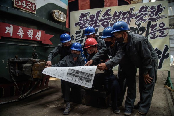 Employees of the Kim Jong Thae Electric Locomotive Complex pose for a photo as they read a copy of the Rodong Sinmun newspaper covering North Korea’s demolition of the North-South joint liaison office, in Pyongyang on June 17, 2020. Photo: AFP