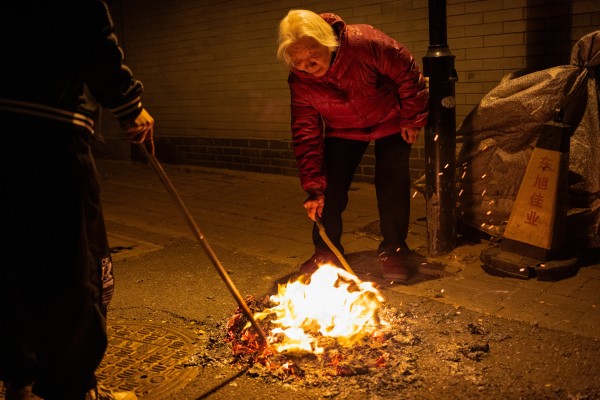 A woman burns paper money in the street as part of a tomb-sweeping ritual in Beijing on Thursday. Photo: EPA-EFE