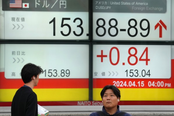 Pedestrians walk past a display showing the yen-US dollar exchange rate in Tokyo. The yen declined below the 153 level for the first time in 34 years on Monday. Photo: EPA-EFE