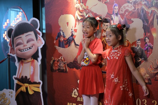 Children pose for photos on Sunday in front of a poster at the Singapore premiere of the Chinese animated film “Ne Zha 2”, which saw its global box office haul top US$2 billion on Monday. Photo: Xinhua
