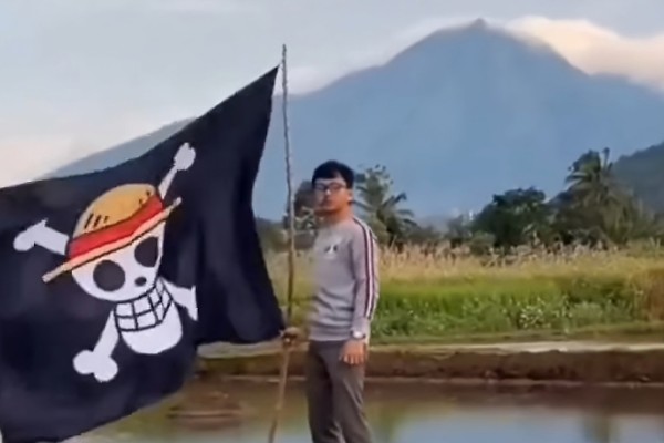 A man in Indonesia holds a One Piece flag with an active volcano in the background. Photo: Facebook