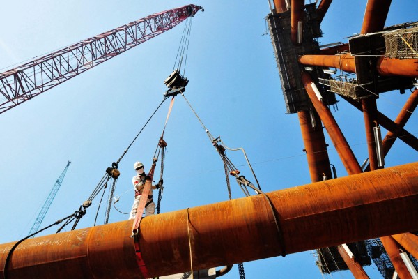A worker stands on pipes at an offshore oil engineering company in China’s Shandong province. Photo: AFP