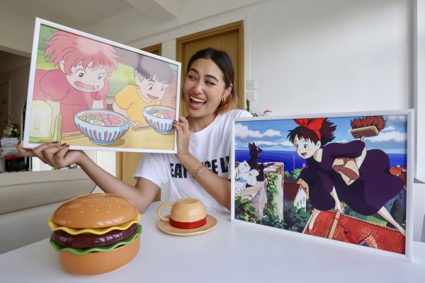 Lukian Wang holds a picture of a scene from Studio Ghibli’s 2008 anime Ponyo at her home in Tsim Sha Tsui, Hong Kong. Her first viral video was of her making instant noodles inspired by food in the film. Photo: Jonathan Wong