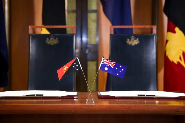 The flags of Australia and Papua New Guinea are displayed on a desk at Parliament House in Canberra on Monday. Photo: AFP