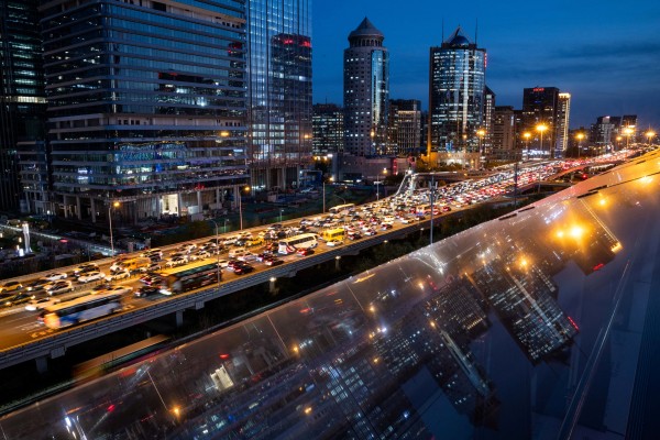 Traffic crawls on an elevated highway as buildings are reflected on a glass surface in Beijing’s central business district on November 12, 2025. Photo: Reuters